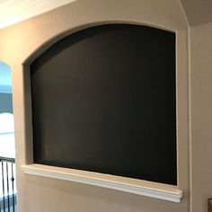 an arched window in the corner of a room with a blackboard on it's wall