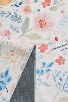 the fabric has flowers on it and is white with blue, pink, yellow and orange colors