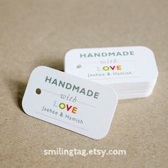 two tags with the words handmade and love printed on them sitting on a table