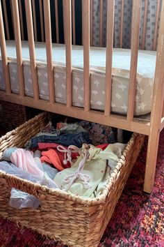 a wicker basket under a crib filled with clothes