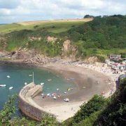 an aerial view of a beach with boats in the water and green hills around it