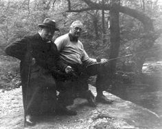 an old photo of two men sitting in the woods with one holding on to his leg