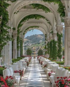 an outdoor seating area with flowers and greenery on the walls, along with white couches