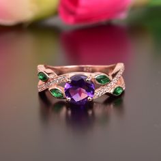 a ring with an amethorate and emeralds on it sitting on a table