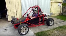 a man driving a red go kart in front of a building with an open door