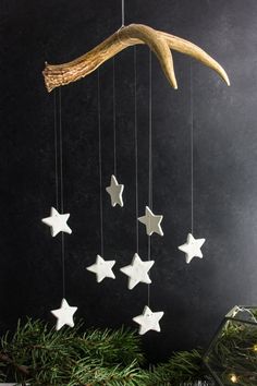 an ornament with stars hanging from it's sides and a tree branch in the background