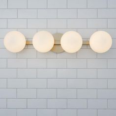 three round lights mounted on the side of a white brick wall