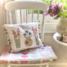 a white chair sitting next to a window filled with flowers