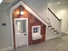 a dog house built into the side of a wall next to a stair case and window