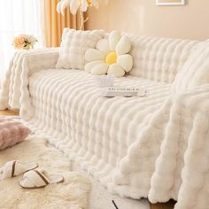 a couch covered in white fur with a flower on it