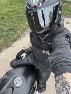 a person wearing a helmet and gloves on a motorbike with grass in the background