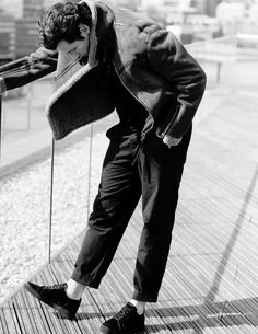 black and white photograph of man leaning on railing