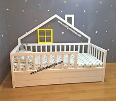 a white crib with a yellow house on top and stars painted on the wall