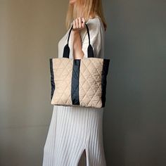 a woman is holding a quilted tote bag