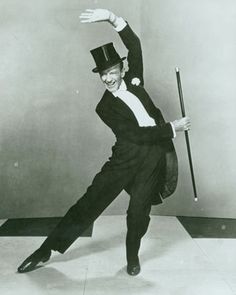 a man in a suit and top hat is dancing with a cane on the floor