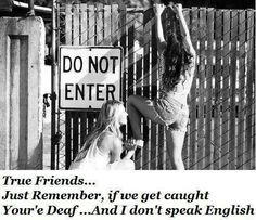 two young women standing next to a fence with a do not enter sign behind them