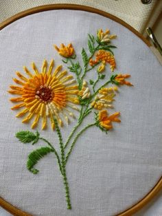 a close up of a embroidery on a white cloth with orange and yellow flowers in it