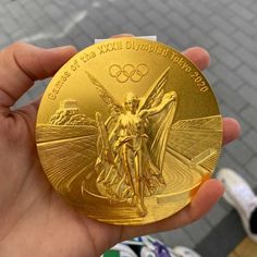 a person holding up a gold medal in their hand