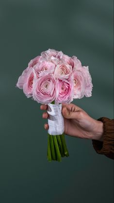 a hand holding a bouquet of pink roses