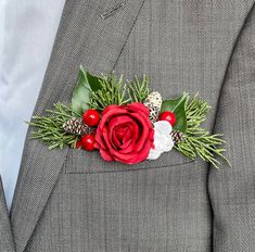 a man in a suit with a red rose and pine cones on his lapel