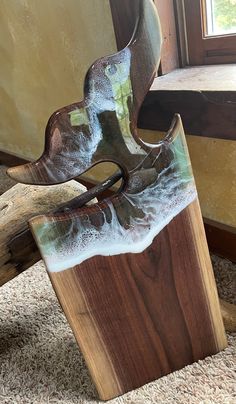 a wooden sculpture sitting on top of a carpeted floor next to a windowsill