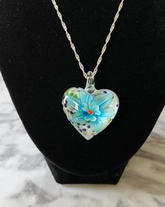 a heart shaped glass necklace on a mannequin neckle with polka dots and a blue flower