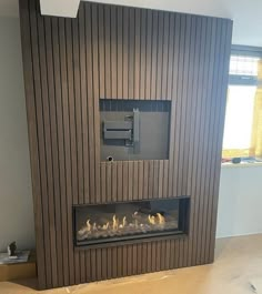 a modern fireplace with wood paneling on the wall and fire place in front of it