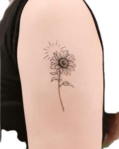 a sunflower tattoo on the back of a woman's left arm and shoulder