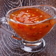 a glass bowl filled with sauce on top of a wooden table