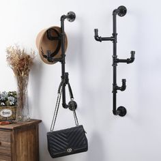 a wall mounted coat rack with two hooks and a purse hanging from it's side