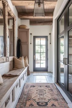 the entryway is decorated in neutral colors and features an antique rug, mirrors, and bench