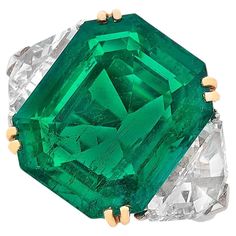 This exquisite ring features a ICA Certified 7.37 carat vivid green emerald as its stunning centerpiece, radiating a rich and captivating hue. Flanking the emerald are two shield-cut diamonds, adding a touch of brilliance and enhancing the ring's luxurious appeal. The emerald is set in an 18k white and yellow gold mounting, providing a perfect contrast that accentuates the vivid green of the gemstone. This ring combines exceptional craftsmanship with elegant design, making it a remarkable additi Green Emerald Ring, Emerald And Diamond Ring, Platinum Diamond Rings, Emerald Diamond Ring, Jewels Rings, Colombian Emeralds, Single Stone, Colored Gems, Fine Jewels