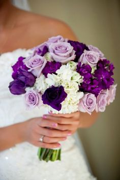 a bride holding a bouquet of purple and white flowers