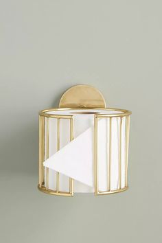 a gold and white napkin holder on a gray wall