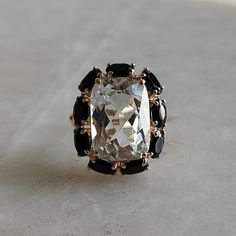 This stunning ring is set in 14k Solid Yellow Gold with Natural White Topaz and Black Spinel with utmost precision. It is a unique statement gemstone ring for nearly every occasion and is completely hassle-free jewelry. ITEM DETAILS: * CENTER GEM: White Topaz * GEM SIZE: 10x14mm * GEM SHAPE: Cushion * SIDE GEM: Black Spinel  * GEM SIZE: 3x5mm (9 pcs) * GEM SHAPE: Oval * Total Gem weight: 12.10 carats * Gold Purity: 14KT (58.33% approx.) * Gold Weight: 2.56 gram * Total Weight of the Ring: 4.98 g Elegant Multi-stone Topaz Ring In 14k Gold, Luxury Black Spinel Jewelry For Wedding, Black Spinel Gemstone Jewelry For Wedding, Elegant Black Spinel Diamond Ring For Wedding, Elegant Black Gemstone Diamond Ring For Wedding, Elegant Black Spinel Sapphire Ring For Wedding, Elegant Sapphire Ring With Black Spinel For Wedding, Wedding Rings With Rose Cut Diamonds And Black Spinel, Black Spinel Fine Jewelry For Wedding