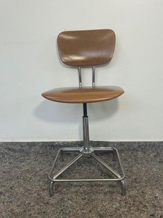 a brown office chair sitting in front of a white wall