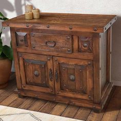 a wooden cabinet sitting on top of a hard wood floor next to a potted plant