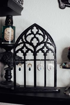 a black shelf with earrings on it next to a bottle and other items in the background