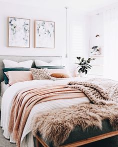 a bedroom with white walls, pink and gray bedding, two pictures on the wall