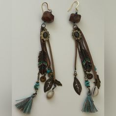 “These Handcrafted Boho-Chic Earrings Exude A Tribal Vibe, Featuring A Stunning Combination Of Raw Green Garnet, Turquoise Accents, And Soft Suede For A Unique Earthy Feel. Each Earring Showcases Intricate Charms, Including Feathers, Seashells, And Tassels, Adding Layers Of Texture And Movement. Lightweight And Full Of Character, These Earrings Are Perfect For Free-Spirited Souls Looking To Add A Statement Piece To Their Jewelry Collection. Elevate Your Style With These One-Of-A-Kind, Artisan-Cr Boho Chic Earrings, Turquoise Accents, Green Garnet, Soft Suede, Free Spirit, Artisan Jewelry, Garnet, Boho Chic, Sea Shells