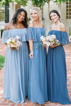 three bridesmaids in blue dresses posing for the camera