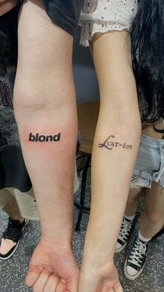 two people holding hands with tattoos on their arms and the words blond written across them