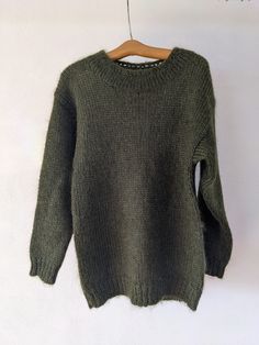 a green sweater hanging on a wooden hanger