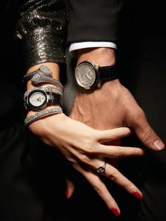 two people wearing wrist watches and bracelets with their hands on each other's wrists