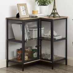 an open glass cabinet with shelves in the corner next to a potted plant and other items