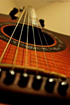 an acoustic guitar is shown close up on the neck and fret, showing the strings