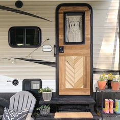 the front door of a mobile home with chairs and potted plants