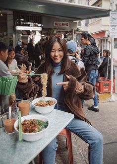 a woman sitting at a table with food in front of her and pointing to the side