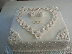 a wedding cake decorated with swans and flowers on a white tablecloth covered table top