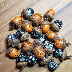 several acorns with designs on them sitting on a wooden table next to some pine cones